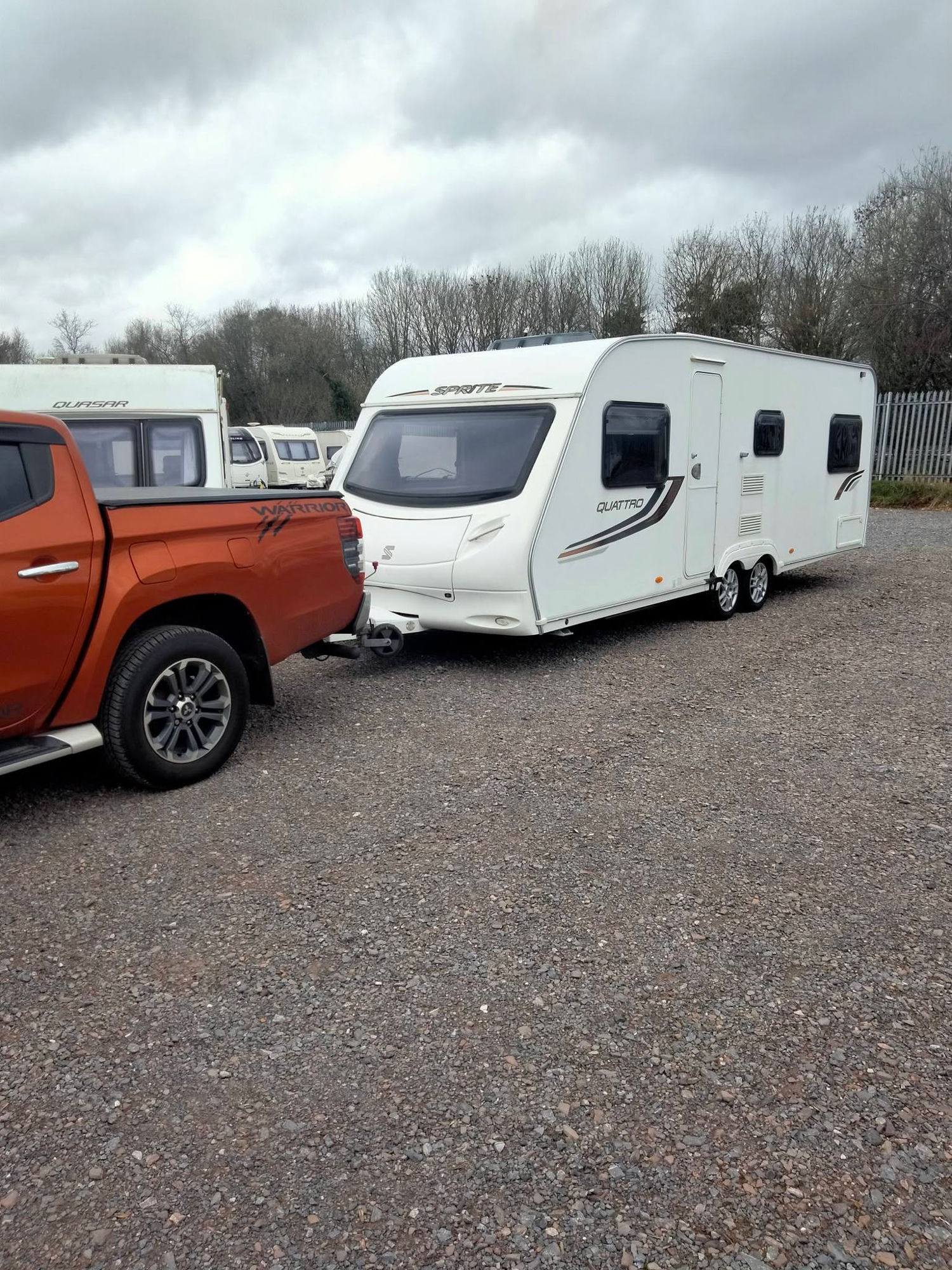 SJS Caravans' pickup towing a white touring caravan on the yard